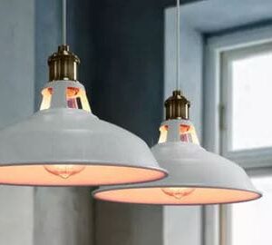 Elsa Smooth Metallic Chic Pot-Lid Pendant Light - Two vintage-style pendant lights hanging from the ceiling. The lights have a white metal shade with a brass fitting and a visible filament bulb.