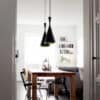 Judit Arabic Inspired Pendant Light - A modern dining room with a long wooden table and black chairs. Three black pendant lights with a unique teardrop shape hang above the table, providing ample lighting.