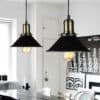 Agda Loft Black English Street Style Pendant Light - Two vintage-style pendant lights hanging from the ceiling above a dining table. The lights have black shades with a gold-colored fitting and visible filament bulbs.